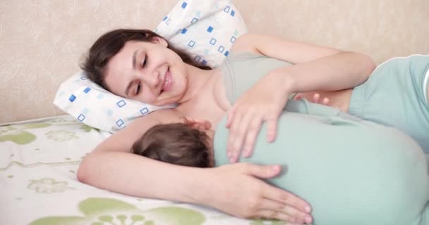 Ευτυχισμένη μαμά χαμογελάει με ευτυχία θηλάζει το μικρό της γιο στο κρεβάτι — Αρχείο Βίντεο