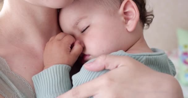 Mãe segura seu filho bebê dormindo em casa e o agita. menino dormindo em seus braços mãe — Vídeo de Stock