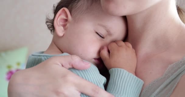 Mãe segura seu filho bebê dormindo em casa e o agita. menino dormindo em seus braços mãe — Vídeo de Stock
