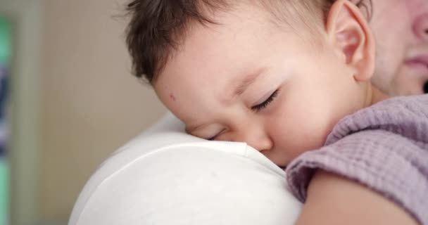 Um bebé pequeno adormeceu nos braços dos pais. pai balançando o bebê para dormir em casa. close-up — Vídeo de Stock