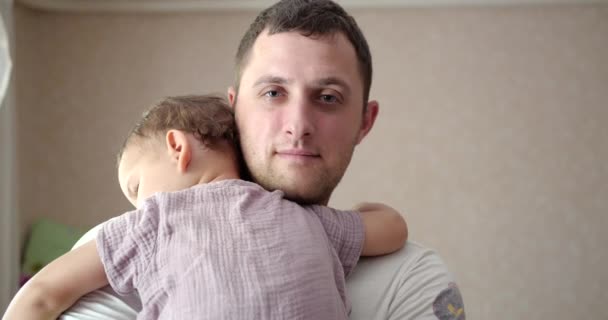 Ένα μωρό αποκοιμήθηκε στην αγκαλιά του πατέρα του. Ο μπαμπάς κουνάει το μωρό για να κοιμηθεί στο σπίτι. κοντινό πλάνο — Αρχείο Βίντεο