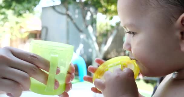 子供の椅子に座っている小さな男の子の肖像画。幸せな子供はカップからミルク、ケフィアまたは乳製品を飲む。子供のための正しく自然な栄養 — ストック動画