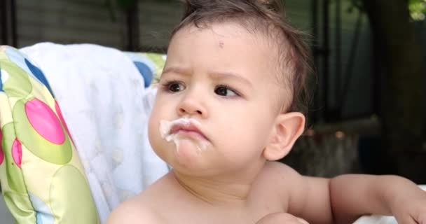 Retrato de un niño que se sienta en una silla infantil. El niño feliz bebe leche, kéfir o productos lácteos de una taza. Nutrición correcta y natural para niños — Vídeos de Stock