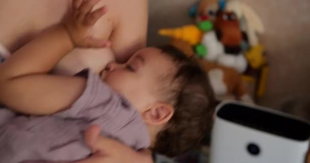 Ένα μικρό παιδί κοιμάται ήσυχα στο στήθος της μητέρας. Η μαμά κουνάει το μωρό στην αγκαλιά της — Αρχείο Βίντεο