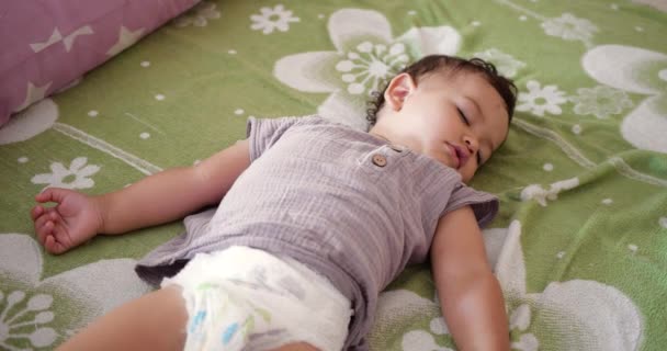 Sevimli küçük çocuk tatlı tatlı uyuyor ve yatak odasında uyurken renkli rüyalar görüyor. — Stok video