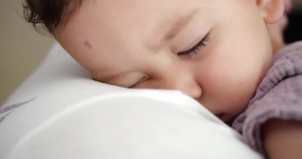 Un pequeño bebé se durmió en los brazos de sus padres. Papá meciendo al bebé para dormir en casa. primer plano — Vídeo de stock