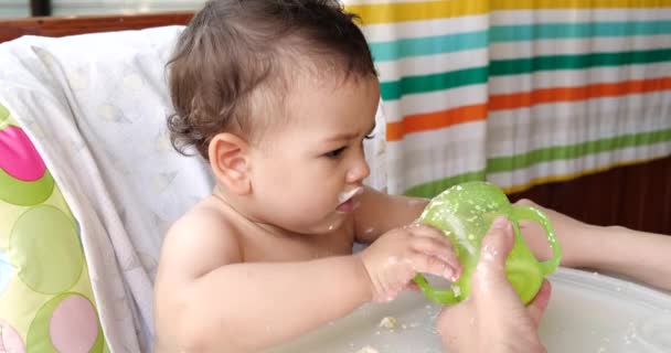 Portrait d'un petit garçon assis sur une chaise d'enfant. Un enfant heureux boit du lait, du kéfir ou des produits laitiers dans une tasse. Une nutrition correcte et naturelle pour les enfants — Video