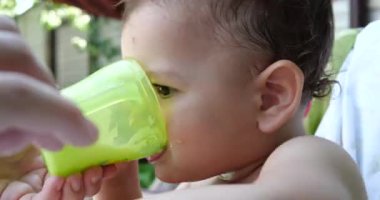 Çocuk sandalyesinde oturan küçük bir çocuğun portresi. Mutlu çocuk bir kupadan süt, kefir ya da süt ürünleri içer. Çocuklar için doğru ve doğal beslenme