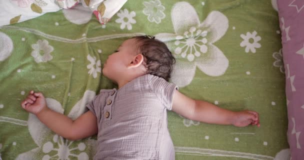 Lindo niño duerme dulcemente en cuna y ve sueños coloridos en el dormitorio mientras duerme en casa — Vídeo de stock