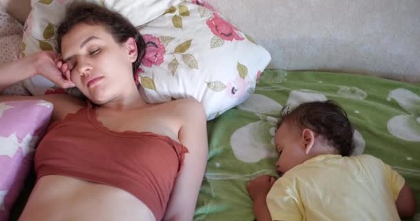 Anne o uyurken küçük oğlunu öpüyor. Uykulu anne bebeği bir öpücükle uyandırır. Oğlu iyi bir ruh hali içinde uyanır. — Stok video