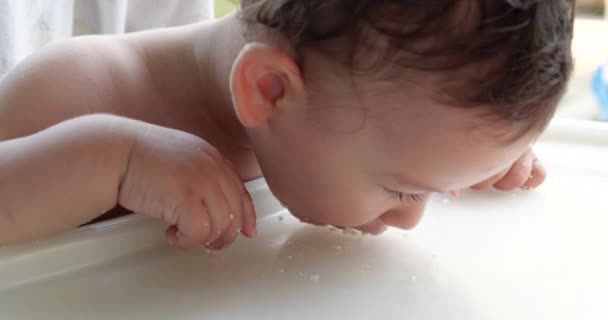 Portret van een kind dat babyvoeding eet met zijn lepel. moeder voedt het kind buiten aan de kindertafel — Stockvideo