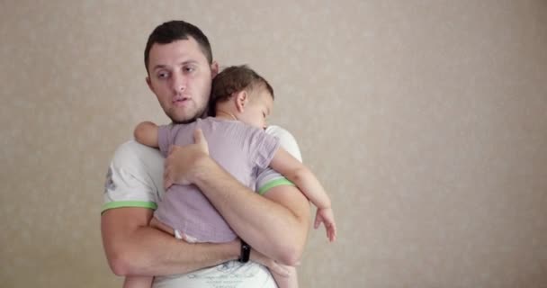 Ein kleines Baby schlief in den Armen seines Vaters ein. Papa schaukelt das Baby zu Hause zum Schlafen. Nahaufnahme — Stockvideo