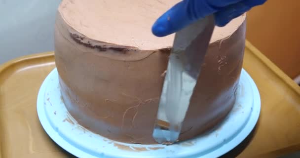 Confiseur femme est la crème à tartiner sur les côtés du gâteau à l'aide de spatule, vue rapprochée. concept culinaire, de cuisson et de cuisson des aliments, cuisine maison — Video