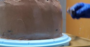 Şekerci kadın pastaya spatula kullanarak krema sürüyor. Yakın çekim. Yemek pişirme, yemek pişirme, ev yemeği.