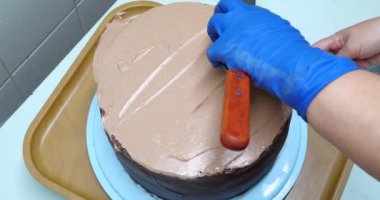 Şekerci kadın pastaya spatula kullanarak krema sürüyor. Yakın çekim. Yemek pişirme, yemek pişirme, ev yemeği.