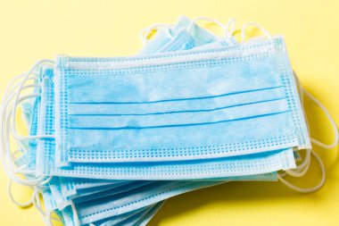 Renkli arka plandaki tıbbi maske yığınına yazılan virüs salgınını kapat. Wuhan virüsü. Dünya salgını.