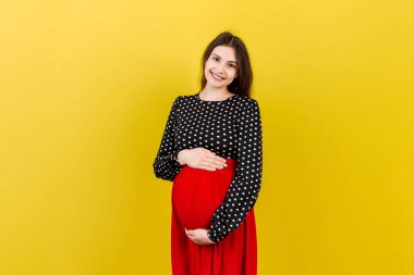 Mutlu hamile kadın renkli arka planda karnına dokunuyor. Müstakbel anne beyaz iç çamaşırı giyiyor. Bir bebek bekliyorduk. Boşluğu kopyala.