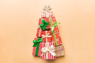 Christmas tree made of beautifuly wrapped presents on colored background, view from above. New Year gift box minimal concept with copy space. clipart