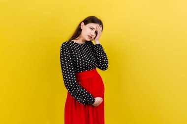 Güzel, genç, hamile bir kadın, renkli bir arka planda baş ağrısı çekiyor. Stresli hamile kadın ya da anne sorunları.