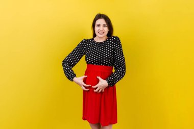 Karnını renkli arka planda kaşıyan hamile bir kadın..