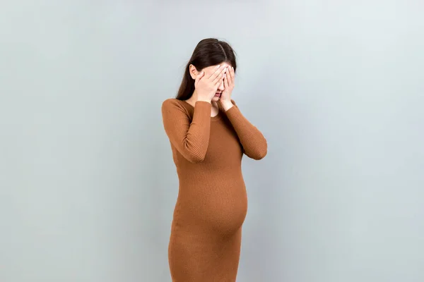 漂亮的年轻孕妇在彩色背景下感到头痛医脚 压力大的孕妇或母亲问题 — 图库照片