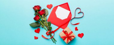 Zarflı sevgililer günü kompozisyonu, gül çiçeği ve kırmızı kalp masada. Üst manzara, düz yatış. Tatil kavramı.