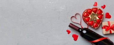 Sevgililer Günü için renkli arka planda bir şişe kırmızı şarap hediye ve çikolatalı. Kalp, hediye kutusuyla şekillendirilmiş çikolatalar fotokopi alanı ile üst görünüm.