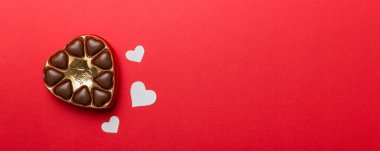 Sevgililer Günü için kırmızı kutuda lezzetli çikolatalı pralinler. Kalp şeklinde çikolata kutusu, fotokopi alanı ile üst görünüm..