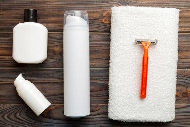 Tıraş Adam seti. Traş makinesi, havlu, losyon ve renkli arka planda tıraş köpüğü. Erkekler banyo aksesuarları üst görünüm.