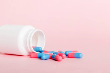 Renkli arka planda haplarla dolu plastik ilaç şişesi. İnternetteki eczane. Ağrı kesici ilaç ve antibiyotik ilaç direnci konsepti. İlaç endüstrisi..