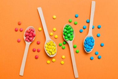 Renkli arka planda kaşık üzerinde renkli tatlı şekerler. Fotokopi alanı ile şekerleme dekoru üst görünümü.