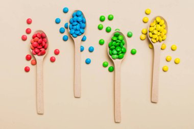 Renkli arka planda kaşık üzerinde renkli tatlı şekerler. Fotokopi alanı ile şekerleme dekoru üst görünümü.