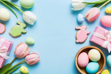 Yumurtalı Paskalya çerçevesi, renkli bir arka planda hediye kutusu ve lale. Minimum konsept. Üst Manzara Mutlu Paskalyalar kompozisyonu. Metin için yerin bir kopyasına sahip kart.