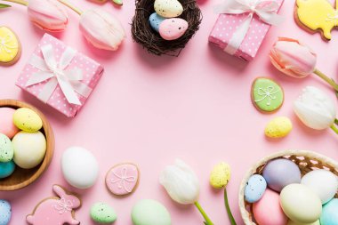 Yumurtalı Paskalya çerçevesi, renkli bir arka planda hediye kutusu ve lale. Minimum konsept. Üst Manzara Mutlu Paskalyalar kompozisyonu. Metin için yerin bir kopyasına sahip kart.