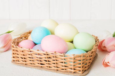 Mutlu Paskalya kompozisyonu. Renkli masada sarı laleli sepetli Paskalya yumurtaları. Fotokopi alanı olan doğal renkli yumurtalar.