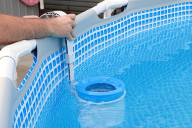 Adam çerçeveli havuz için kaymağını temizliyor. Kirli havuz temizleme konsepti.