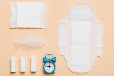 Alarm saatini hijyenik kadın tamponları ve regl pedleri ile çalıyor. Tıbbi konsept kadın kritik günler ve regl dönemi. Kadın günlük hijyen. Boşluğu kopyala.
