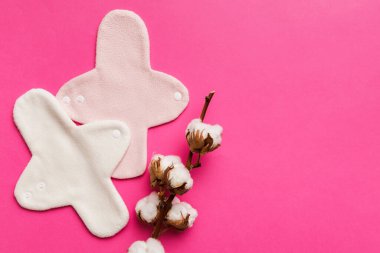 Üzerinde pamuk çiçekleri olan renkli, yeniden kullanılabilir adet pedleri. sıfır atık kadın dönemi konsepti kopya alanı ile üst görünüm.