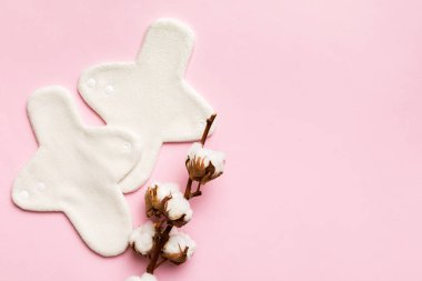 Üzerinde pamuk çiçekleri olan renkli, yeniden kullanılabilir adet pedleri. sıfır atık kadın dönemi konsepti kopya alanı ile üst görünüm.