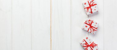 Sevgililer veya diğer tatil el yapımı mevcut kağıt ile tatil sarmalayıcı kırmızı kalpler ve hediye kutusunda. Tasarım için kopya alanı görünümüyle Beyaz ahşap masa üstü, boş alanı kutusu hediye sunmak.