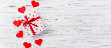 Sevgililer veya diğer tatil el yapımı mevcut kağıt ile tatil sarmalayıcı kırmızı kalpler ve hediye kutusunda. Tasarım için kopya alanı görünümüyle Beyaz ahşap masa üstü, boş alanı hediye kutusu.