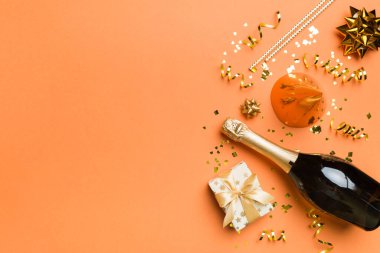 Renkli arka planda şampanya şişesi hediye paketi kurdeleleri ve konfetilerin düz kompozisyonu vardı. Düz konum, üst görünüm tatil konsepti.