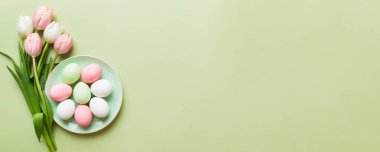 Mutlu Paskalya kompozisyonu. Renkli masada sarı laleli sepetli Paskalya yumurtaları. Doğal boyalı renkli yumurtalar arkaplan arkaplan görünümü kopya alanı ile.
