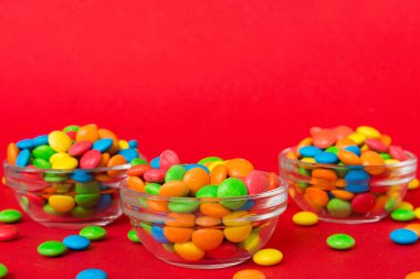 Renkli arka planda bir kasede çok renkli şekerler. Doğum günü ve tatil konsepti. Kopyalama alanı olan üst görünüm.