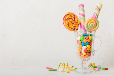 Masanın üzerinde açık arkaplanda renkli şekerler. Büyük kıvrımlı lolipoplar. Şekerci dükkanından leziz şekerlerle dolu yaratıcı bir kavanoz konsepti.