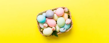 Mutlu Paskalyalar. Renkli masada sarı güllerle birlikte Paskalya yumurtaları. Doğal boyalı renkli yumurtalar arkaplan arkaplan görünümü kopya alanı ile.