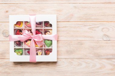 Box with sweet chocolate candies on color background, Various candy sweets. Valentines day gift box. Top view flat lay with copy space.