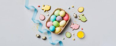 Renkli paskalya kurabiyeleri sepette renkli arka planda çok renkli Paskalya yumurtaları. Pastel renginde Paskalya yumurtası. Kopyalama alanı olan tatil kavramı.