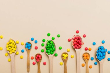 Renkli arka planda kaşık üzerinde renkli tatlı şekerler. Fotokopi alanı ile şekerleme dekoru üst görünümü.