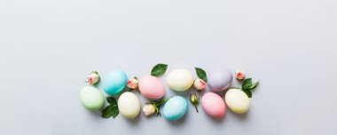 Mutlu Paskalyalar. Renkli masada sarı güllü Paskalya yumurtaları. Doğal boyalı renkli yumurtalar arkaplan arkaplan görünümü kopya alanı ile.